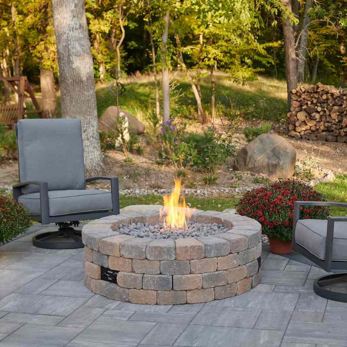 Bronson Block Round Gas Fire Pit Kit Placed at Frontyard with Tumbled Lava Rock Scaled plus Fire Burner On