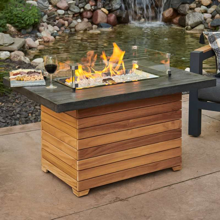 Darien Rectangular Gas Fire Pit Table with Aluminum Top with Clear Tempered Fire Glass Gems On Fire, Gas Tank Door Open near Pond with Wine