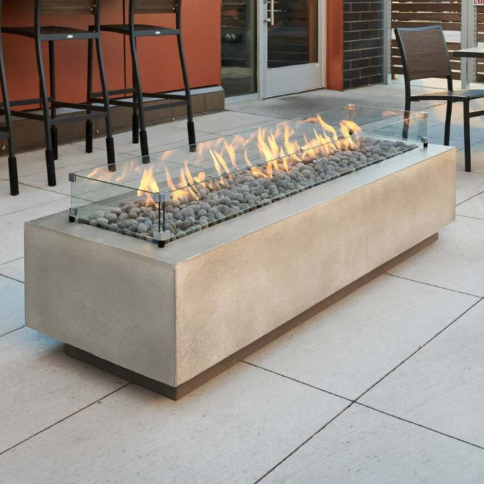 Natural Grey Cove 72 Linear Gas Fire Pit Table at the Front Yard with Tumbled Lava Rock plus Fire Burner On and Glass Wind Guard Installed