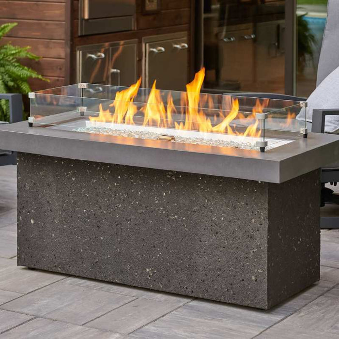 The Outdoor Greatroom Midnight Mist Key Largo Linear Gas Fire Pit Table Placed at the Deck with Clear Tempered Fire Glass Gems plus Fire Burner On and Glass Wind Guard