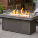 The Outdoor Greatroom Midnight Mist Key Largo Linear Gas Fire Pit Table Placed at the Deck with Clear Tempered Fire Glass Gems plus Fire Burner On and Glass Wind Guard